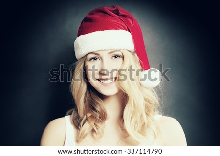 Christmas Girl. Smiling Woman in Santa Hat on Dark Background