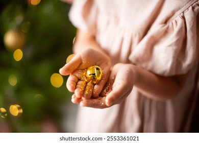 Christmas golden bell on the hands of a little girl. lights create a cozy holiday atmosphere. - Powered by Shutterstock