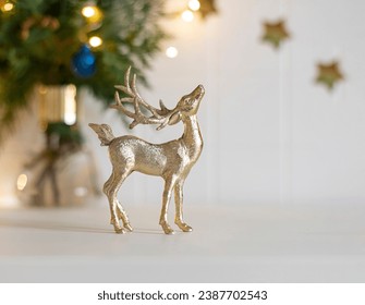 Christmas golden deer toy on the white chest of drawers. Winter holiday decoration close up. Copy space - Powered by Shutterstock