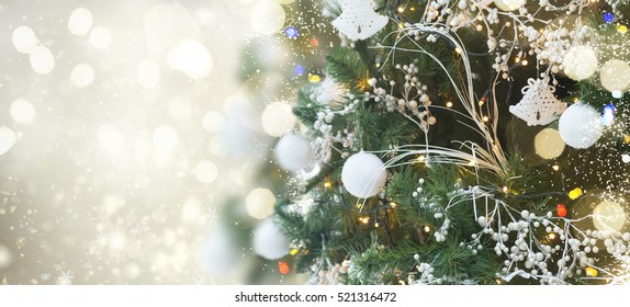 christmas green tree with holiday white  decorations and lights with copy space on silver bokeh background banner