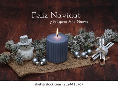 Christmas greeting card: Blue burning candle with fir branches, cinnamon stars and snowman decoration figure on rustic wood. Spanish inscription means Merry Christmas and a Happy New Year. - Powered by Shutterstock