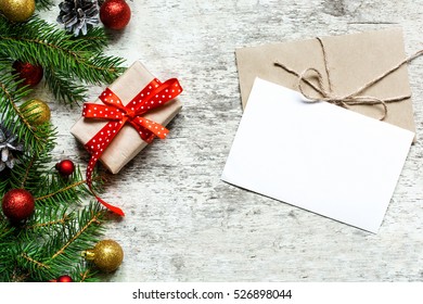 christmas greeting card with envelope and gift box on white wooden background with fir tree branches and happy new year decorations - Powered by Shutterstock