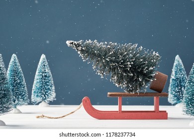 Christmas Greeting Card Place For Your Text. Noel. A Bright Christmas Tree Toy In Form Of Fir Tree On Santa Claus Sleigh On Dark Background Toy Christmas Trees In The Background. Snowing. Front View