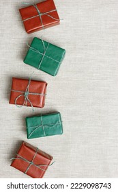 Christmas handmade gift boxes on textile background, craft paper-wrapped presents with rough string, Christmas colors gifts. Top view on set handcrafted gifts for holidays with copy space for text