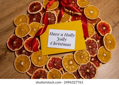 Christmas handmade wreath made of dried slices of orange and grapefruit with yellow envelope and paper note with HAVE A HOLLY JOLLY CHRISTMAS text. Winter holiday celebration greeting card - Powered by Shutterstock