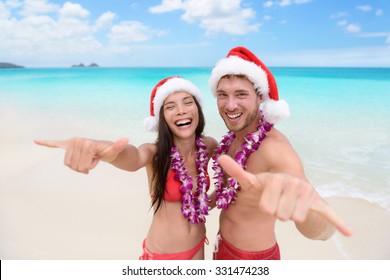 Christmas Hawaii Vacation - Hawaiian Beach Couple Wearing Santa Hat And Doing Welcome Shaka Sign Happy At Camera As Welcoming Gesture For Winter Holidays.