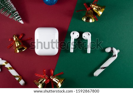 christmas headphones. Air Pods. with Wireless Charging Case. New Airpods 2020 on green background. Air Pods on Christmas background.wireless headphones with Christmas toys