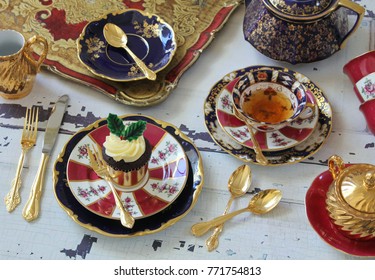 Christmas High Tea Party - Vintage Bone China Red And Dark Blue Teacups, Teapot, Gold Cutlery Flatware On A Distressed Wood Table