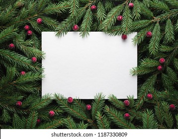 Christmas holiday background with copy space for text. Flat lay, top view. Decorative frame of fir branches and holly berries. Paper notice sheet - Powered by Shutterstock