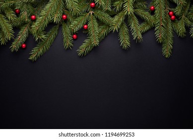 Christmas Holiday Background With Copy Space For Advertising Text. Fir Branches And Holly Berries On Black. Flat Lay, Top View