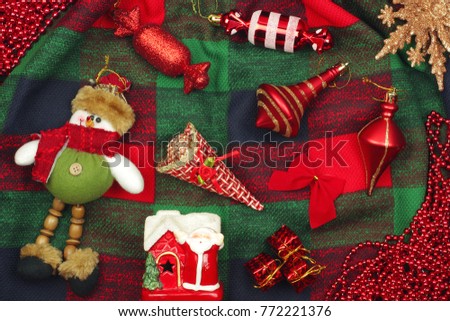 Christmas holiday background with red house, Santa Claus, snowman, bells, gifts, garlands and decorations on tartan cloth. Top view.
