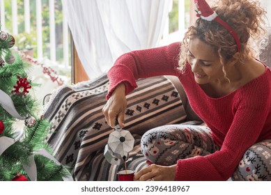 Christmas holiday celebration alone with happy adult woman at home on 25 december after xmas eve having breakfast with a coffee. People with santa claus hat in real leisure activity indoor. New year - Shutterstock ID 2396418967