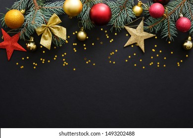 Christmas Holiday Composition. Festive Christmas Decorations, Baubles, Fir Tree Branches, Confetti Star On Dark Black Background With Copy Space. Banner Mockup, Postcard. Flat Lay, Top View, Overhead