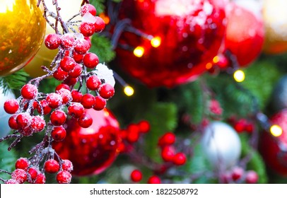 Christmas Holiday Decoration Background, Close-up. Festive Beads, Red Berries, Xmas Tree Balls Toys On Christmas Tree, Garland Illumination