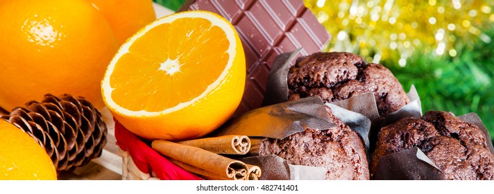 Christmas holiday panoramic still life with muffins, cinnamon sticks, oranges, chocolate and Christmas tree background - Powered by Shutterstock