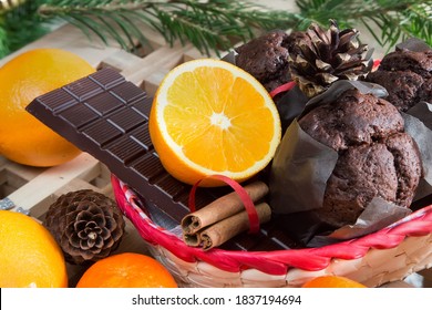 Christmas holiday still life with close-up muffins, cinnamon sticks, oranges, chocolate and pine cone on Christmas tree background - Powered by Shutterstock