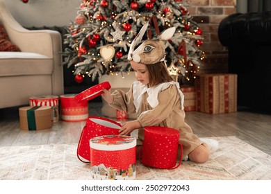 Christmas holidays concept. Happy magic little girl opens a gift box. Child is happy with a New Year's gift. The background is Christmas tree. The concept of Christmas and New Year. High quality photo - Powered by Shutterstock