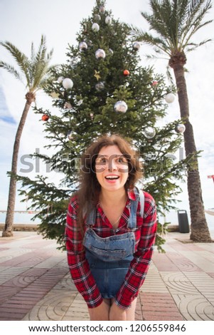 Christmas, holidays, humor and people concept - young happy woman have fun under the christmas tree