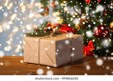 Christmas, Holidays, Presents, New Year And Decor Concept - Close Up Of Gift Box Wrapped Into Brown Mail Paper And Decorated With Fir Brunch And Rope Bow Over Lights Background