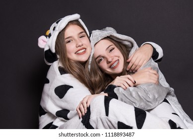 Christmas Holidays. Two Children, Sisters Are Wearing Animal Pajamas. Merry Christmas Or Halloween Concept. Family Holiday, Party Over Black Background. Cute Teenage Sisters. Teen. Hugging.