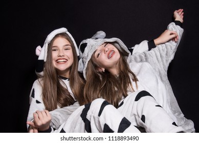 Christmas Holidays. Two Children, Sisters Are Wearing Animal Pajamas. Merry Christmas Or Halloween Concept. Family Holiday, Party Over Black Background. Cute Teenage Sisters. Teen. Hugging.