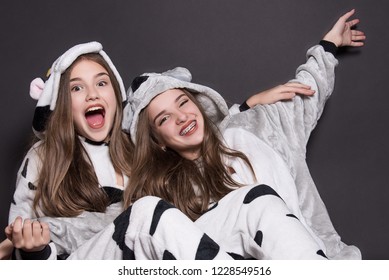 Christmas Holidays. Two Children, Sisters Are Wearing Animal Pajamas. Merry Christmas Or Halloween Concept. Family Holiday, Party Over Black Background. Cute Teenage Sisters. Teen. Hugging.