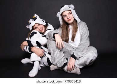 Christmas Holidays. Two Children, Sisters Are Wearing Animal Pajamas. Merry Christmas And Happy Holidays Concept. Family Holiday, Party Over Black Background. Cute Teenage Sisters.  