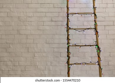 Christmas holidays. Wooden ladder in colored lights on bricks background, copy space - Powered by Shutterstock