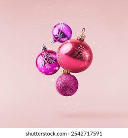 Christmas holliday image, purple, violet, pink Christmas baubles  falling in the air isolated on pink background - Powered by Shutterstock