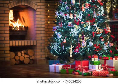 Christmas home interior with tree and fireplace. Traditional living room in country house decorated with lights and candles. Big stone open fire place. Xmas gifts and presents. Reindeer decoration.