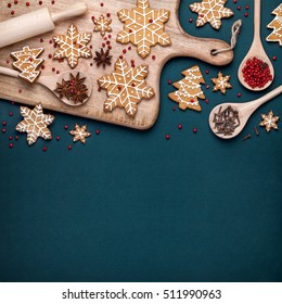 christmas homemade gingerbread cookies, spices and cutting board on dark green background with copy space for text top view. holiday, celebration and cooking concept. new year and christmas postcard