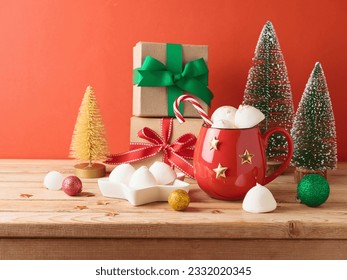 Christmas hot chocolate cup with marshmallow, gift box and decorations on wooden table over red background - Powered by Shutterstock