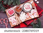 Christmas hot chocolate tray an assortment of sweet toppings. Top view table scene on a dark wood background.