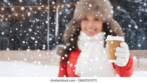 christmas, hot drinks and holidays concept - happy woman with disposable paper coffee cup in winter over outdoor ice skating rink on background - Powered by Shutterstock