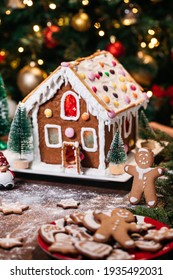 Christmas House From Ginger Cookies With Ginger Man Outside Decorated In Christmas Spirit With Tree In Background