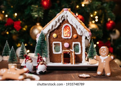 Christmas house  made from ginger cookies with ginger man outside decorated in Christmas spirit with tree in background