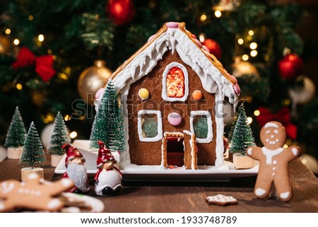 Christmas house  made from ginger cookies with ginger man outside decorated in Christmas spirit with tree in background