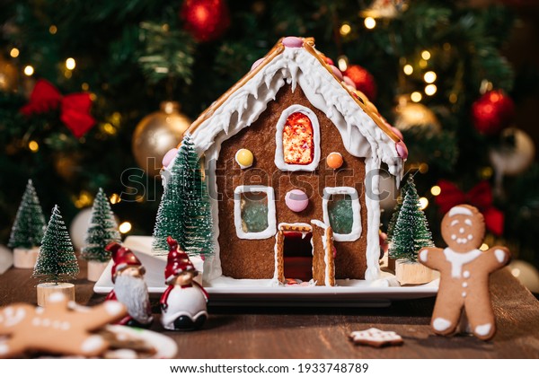 Christmas\
house  made from ginger cookies with ginger man outside decorated\
in Christmas spirit with tree in\
background