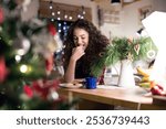 Christmas hygge at home. Beautiful young woman eating christmas cookies and sweets next to the Christmas tree.