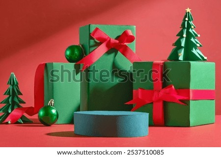 A Christmas image is created by a blue empty circular platform for product displays, next to green present boxes tied with red ribbons, paper pine trees, and green Noel balls against a red background.