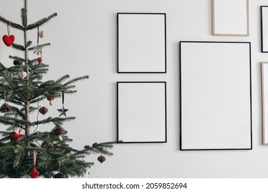 Christmas  interior. Decorated fir tree with hanging traditional winter ornaments. Set of  black and wooden portrait picture frame mockups. Wall art gallery. White wall background. Living rooom.