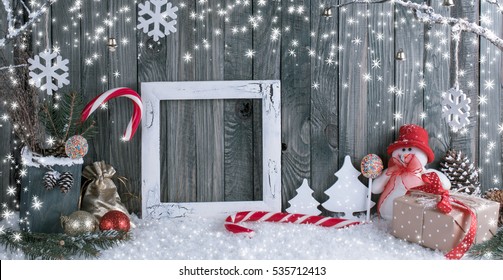 Christmas Interior With Snowman, Photo Frame, Decorative Branches, Presents And Candy Canes On Wooden Planks Background. New Year Winter Composition.  