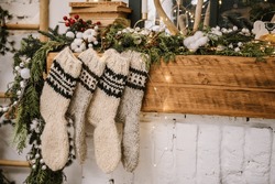 Christmas Knitted Woolen Socks Closeup. Decorative Fireplace With Christmas Stockings, Garlands And Gifts In Stylish Room Interior. Happy New Year And Merry Christmas.