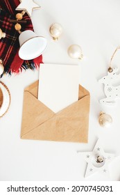 Christmas Letter Mockup. Craft Paper Envelope With Blank Paper Card And Xmas Decorations On White Table. Flat Lay, Top View, Copy Space.