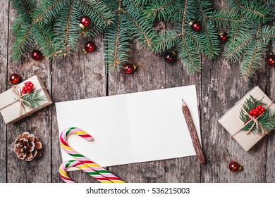 Christmas letter on wooden background with Christmas gifts, Fir branches, candy, red decorations. Xmas and Happy New Year composition. Flat lay, top view - Powered by Shutterstock