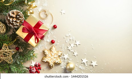 Christmas light gold background with beautiful Golden gift box with red ribbon, fir branches, cones, stars, Christmas cookies, top view, copy space. - Powered by Shutterstock