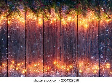 Christmas Light On Vintage Wooden Table - String With Fir Branches And Abstract Defocused Snow Flakes