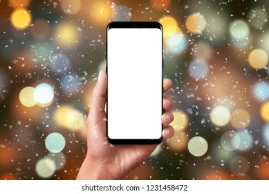 Christmas Lights And Bokeh. Smart Phone In Hand With Isolated Screen For Mockup, App Or Web Site Design Presentation.