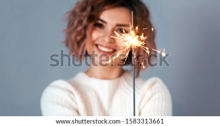Christmas lights bright splashes burn in hands of blurry happy women smile on grey background. Bengali. Noel. Christmas preparation. Emotions Christmas mood and songs, traditions. Winter holidays