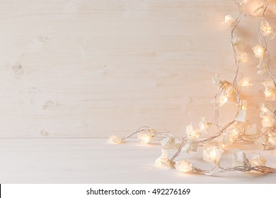 Christmas lights burning  on a white wooden background. Xmas background. - Powered by Shutterstock